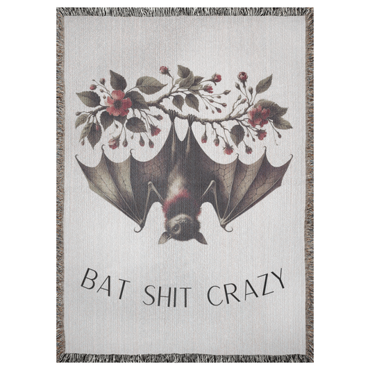 A 37x52 inch woven blanket depicting a bat hanging upside down from a branch with red flowers and green leaves.