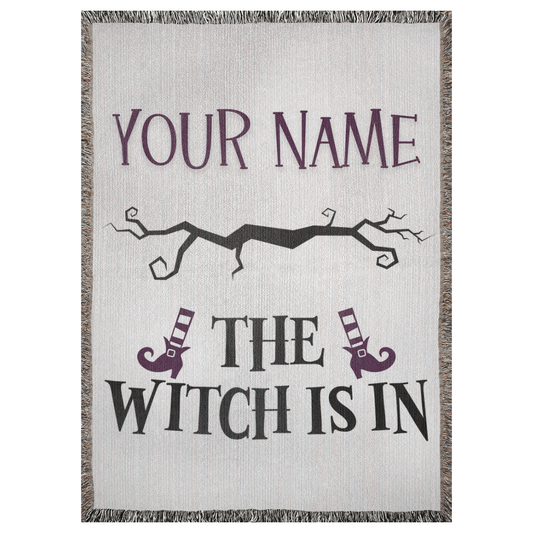 A customizable 37x52 inch woven blanket depicting a spooky branch and witch legs with striped socks and boots. It says "the witch is in".